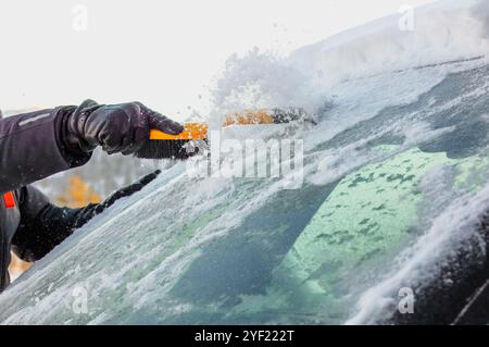 Grattoir à neige dégageant la glace du pare-brise de la voiture, flurries de neige visiblee Banque D'Images