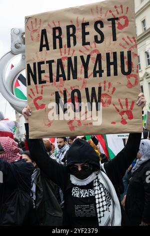 Londres, Royaume-Uni. 2 novembre 2024. Une pancarte appelant à l'arrestation du premier ministre israélien Benjamin Netanyahu est affichée alors que plusieurs milliers de partisans palestiniens organisent la 22e Marche nationale pour la Palestine depuis qu'Israël a lancé des guerres contre Gaza, la Cisjordanie occupée et le Liban à la suite d'une attaque par des militants du Hamas. Se rassemblant à Whitehall avant de marcher vers l'ambassade des États-Unis, la manifestation a appelé à un cessez-le-feu immédiat et à la fin du soutien britannique et américain et des ventes d'armes à Israël. Crédit : Ron Fassbender/Alamy Live News Banque D'Images