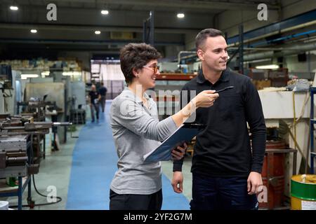 Métallurgiste à l'aide d'une perceuse sans fil en atelier créant des pièces mécaniques personnalisées Banque D'Images