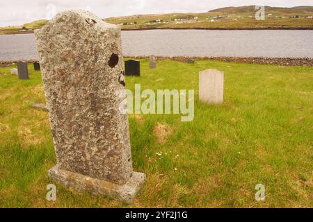 Regardant à travers le Loch Rog an Ear du cimetière de Callanish à Breascleit de l'autre côté avec le dos d'une vieille pierre tombale au premier plan Banque D'Images