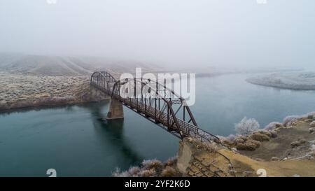 Pont de fer brumeux au-dessus du paysage de la rivière sereine Banque D'Images