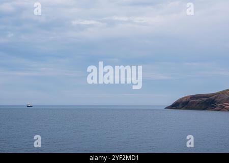 Un bateau d'excursion est amarré au large de la côte de la jeune fille bleue (Bla Jungfrun), une île et un parc national dans le nord du détroit de Kalmar, en Suède. Banque D'Images