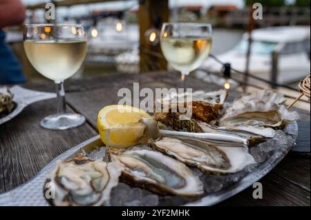 Manger des huîtres fraîches vivantes avec du citron et du pain au café de ferme en plein air dans le village ostréicole, bassin d'Arcachon, port de Gujan-Mestras, Bordeaux, Fran Banque D'Images