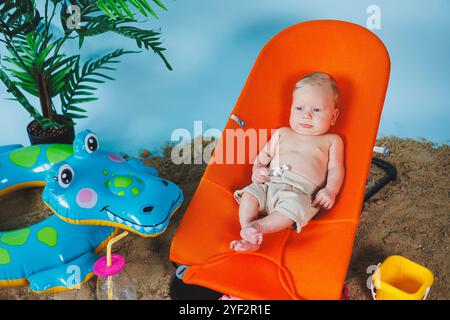 Un bébé est allongé sur un fauteuil inclinable pour bébés. Loisirs pour enfants. Banque D'Images