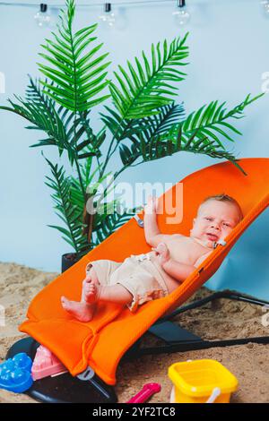 Un bébé est allongé sur un fauteuil inclinable pour bébés. Loisirs pour enfants. Banque D'Images