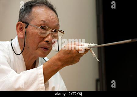 Homme aiguisant une épée japonaise courte appelée wakizashi de manière traditionnelle avec une pierre à aiguiser dans la ville de Seki, Gifu, Japon. Banque D'Images