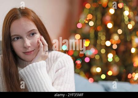 Femme attirante pose souriante avec sa main reposant sur son visage à Noël Banque D'Images