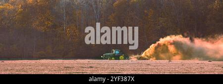 Image panoramique d'un grand tracteur à chenilles tirant un outil de creusement de fossés sur fond de bois en couleur automnale. Beaucoup de poussière Banque D'Images