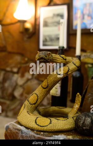 Une sculpture de serpent détaillée s'enroule autour de bouteilles vintage, mettant en valeur la créativité dans une atmosphère chaleureuse. Banque D'Images