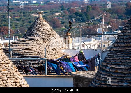 Trulli traditionnel en pierre d'Alberobello avec séchage des vêtements sur les toits, Italie. Banque D'Images