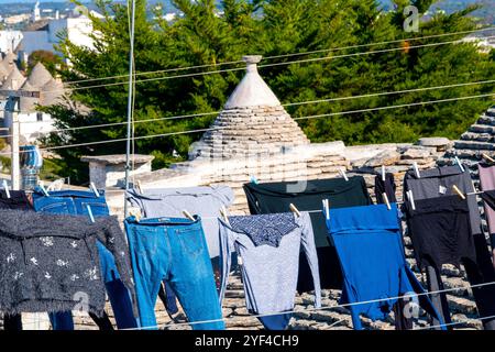 Trulli traditionnel en pierre d'Alberobello avec séchage des vêtements sur les toits, Italie. Banque D'Images