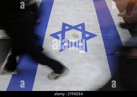 Téhéran, Iran. 3 novembre 2024. Les gens marchent sur un drapeau isréal lors d'un rassemblement anti-américain marquant le 45e anniversaire de la prise de contrôle de l'ambassade américaine devant l'ancien bâtiment de l'ambassade à Téhéran. Le 4 novembre 1979, des étudiants iraniens se sont emparés de l'ambassade des États-Unis à Téhéran, retenant en otage plus de 50 diplomates et gardes américains pendant 444 jours. Et Israël suite à la récente frappe israélienne contre l'Iran. Crédit : ZUMA Press, Inc Crédit : ZUMA Press, Inc/Alamy Live News Banque D'Images