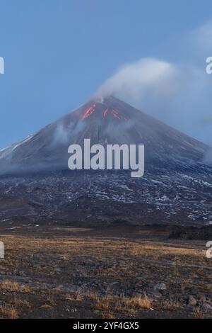 Paysage volcanique du Kamchatka : éruption du volcan Klyuchevskoy, coulées de lave sur la pente du volcan, panache de gaz, vapeur, cendres du cratère. Kamchatka Penins Banque D'Images