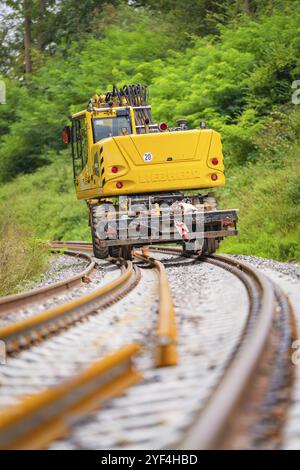 Train jaune circule sur des voies sinueuses à travers un paysage verdoyant, construction de voie, Hermann Hessebahn, Calw, Forêt Noire, Allemagne, Europe Banque D'Images