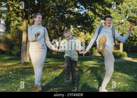 Une maman de la famille et 2 fils s'amusent, courent dans le parc et sautent. Fils, enfants, maman, courir, jouer, réjouissez-vous, profitez de la nature en été. Équipe familiale Banque D'Images