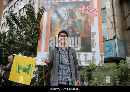 Téhéran, Iran. 3 novembre 2024. Un garçon iranien tient un drapeau du Hezbollah devant une grande bannière représentant une image de Benjamin Netanyahu, le premier ministre israélien, lors d’un rassemblement anti-américain marquant le 45e anniversaire de la prise de contrôle de l’ambassade américaine devant l’ancien bâtiment de l’ambassade à Téhéran. Le 4 novembre 1979, des étudiants iraniens se sont emparés de l'ambassade des États-Unis à Téhéran, retenant en otage plus de 50 diplomates et gardes américains pendant 444 jours. Cette action faisait suite à la décision des États-Unis d'autoriser Shah déchu de l'Iran à recevoir un traitement médical en Amérique. Récemment, le 2 novembre, Supreme le Banque D'Images