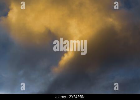 Nuages moelleux illuminés par la disparition des rayons au coucher du soleil et les orages sombres flottant à travers le ciel bleu ensoleillé pour changer le temps de saison. Vue incroyable Banque D'Images