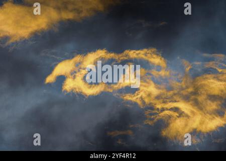 Des nuages d'orage moelleux illuminés par des rayons en train de disparaître au coucher du soleil et des orages sombres qui flottent à travers le ciel bleu pour changer le temps de la saison. Stunni Banque D'Images