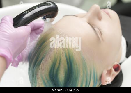 Salon de coiffure professionnel, coiffeur se lavant la tête de client avec la couleur verte des cheveux. Coiffeur de travail: Lave les cheveux avec le shampooing de la jolie jeune femme Banque D'Images