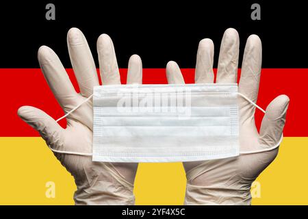 Médecin tenant le masque médical à deux mains dans des gants blancs sur fond drapeau allemand. Concept coronavirus quarantaine, hygiène, grippe, pandémie Banque D'Images