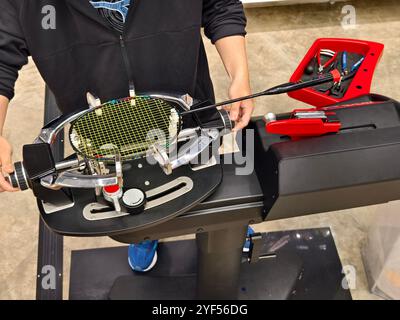 Cordes une raquette de badminton sur une machine à cordes de raquettes. Banque D'Images