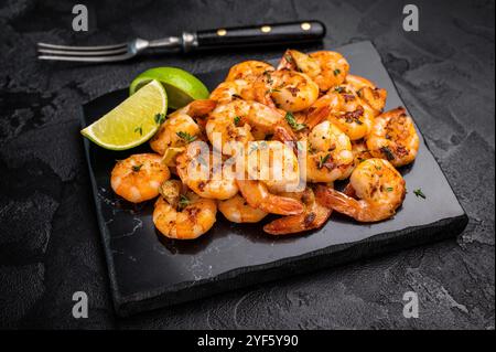 Crevettes épicées grillées au barbecue avec de l'ail. Fond noir. Vue de dessus. Banque D'Images