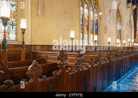 Bancs en bois sombre avec des extrémités de bancs en bois et des portes en bois sculptés de façon complexe à Lincoln’s Inn Chapel, Londres, Angleterre Banque D'Images