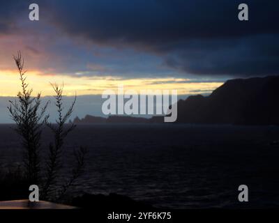 Une vue côtière à couper le souffle alors que les vagues s'écrasent contre d'imposantes falaises, sous un ciel rempli de nuages d'humeur changeante, capturant la puissance brute et la beauté de la nature Banque D'Images