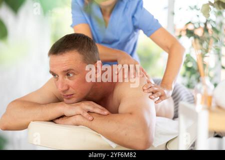 Femme circoncis recadrée effectue un massage du dos au client masculin Banque D'Images