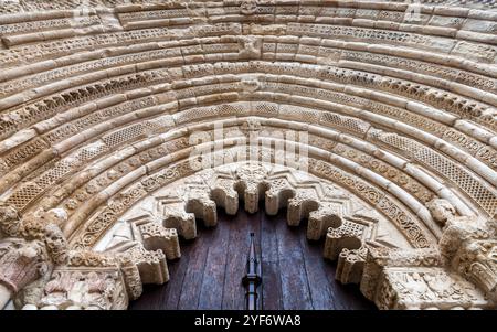 Une arche en pierre magnifiquement sculptée encadre les grandes portes en bois d'une ancienne église d'Estella, mettant en valeur l'artisanat complexe. Banque D'Images
