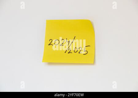 2024 et 2025 écrit sur papier jaune qui est collé sur un fond blanc, nouvelle et ancienne année Banque D'Images