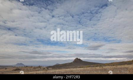 Une vue panoramique sur les collines ondoyantes et les formations de nuages spectaculaires au-dessus d'un paysage paisible pendant l'après-midi dans une zone rurale Banque D'Images