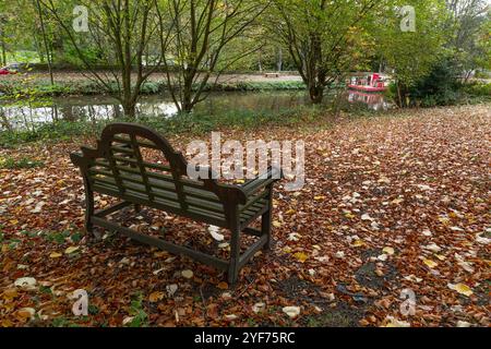 Un siège commémoratif en bois (banc) dans le parc de l'église Saltaire United Memorial. Le siège donne sur le canal de Leeds Liverpool. Prise en automne. Banque D'Images