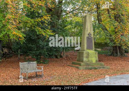 Un mémorial de la première Guerre mondiale dans les terres de l'église réformée unie Saltaire en automne. Un siège commémoratif en bois près du mémorial de l'obélisque. Banque D'Images