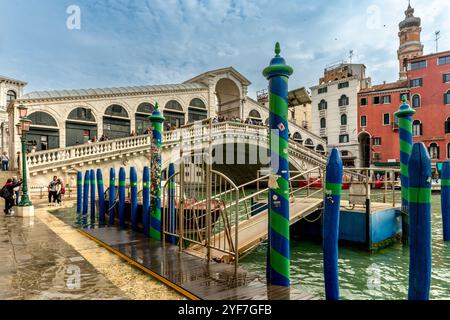 Venise, Vento – IT – Oct 14, 2024 L’emblématique pont du Rialto enjambe le Grand canal de Venise, avec des gondoles amarrées au premier plan et des touristes se promenant Banque D'Images