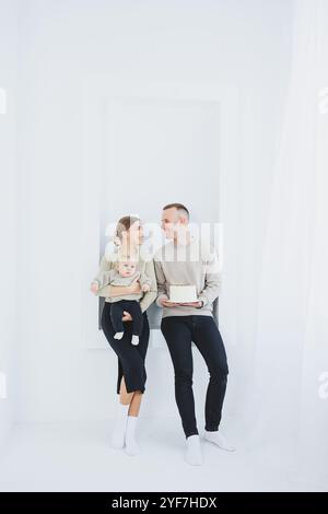 Mère et père souriants tenant un enfant et un gâteau de vacances. Parents maman et papa et bébé souriant dans les bras isolés sur fond blanc. Heureux jeune Banque D'Images