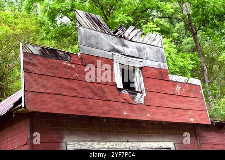 La façade de l'ancien magasin a un dos en bois avec revêtement en amiante rouge. Le bois est en pourriture et le bardage est manquant. Banque D'Images