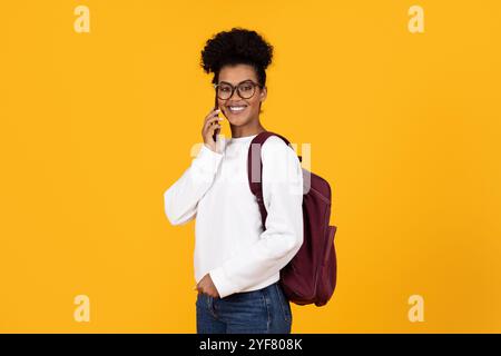 Une jeune femme sourit largement en parlant sur son smartphone Banque D'Images