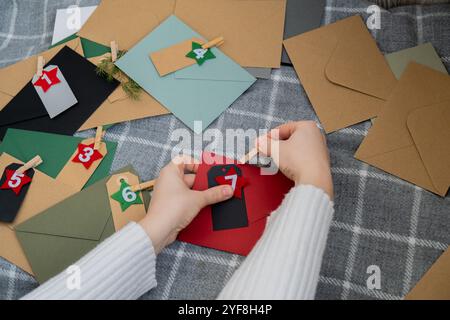 Numéro sur les enveloppes d'artisanat notes avec des tâches avant les vacances de Noël. Femme faisant du papier kraft pour calendrier de l'Avent fait à la main fait de vos propres mains étape par étape bricolage artisanat faites-le vous-même Banque D'Images