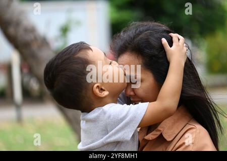 Un moment réconfortant montrant un enfant embrasser son parent sur le front, capturant l'essence de l'amour et de la connexion dans un magnifique décor extérieur Banque D'Images