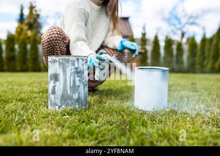 Une femme peint des boîtes en métal de couleur blanche pour planter des plantes et des fleurs Banque D'Images