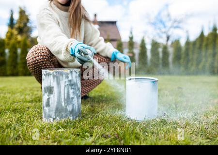 Une femme peint des boîtes en métal de couleur blanche pour planter des plantes et des fleurs Banque D'Images