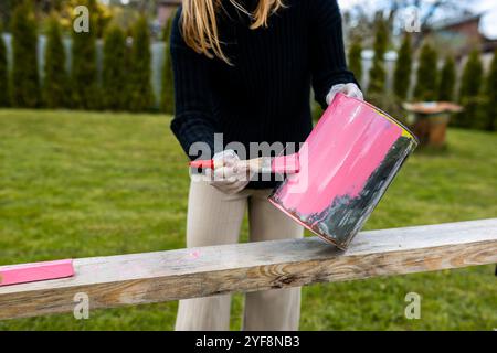 Une femme peint des boîtes de métal en couleur rose pour planter des plantes et des fleurs Banque D'Images