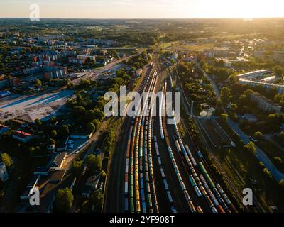 Vue aérienne du train Yard animé adjacent à un paysage urbain pittoresque au coucher du soleil Banque D'Images