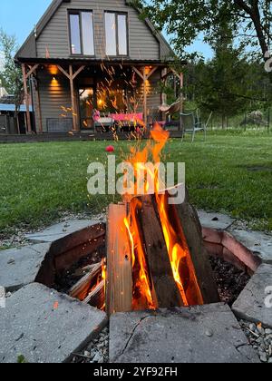 Cozy soirée Bonfire dans la cour arrière avec Sparks Flying et maison privée derrière Banque D'Images