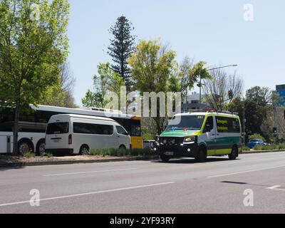 Ambulance voyage le long de Hutt Street par une journée ensoleillée et lumineuse à Adélaïde, en Australie avec bus et van en arrière-plan. Banque D'Images