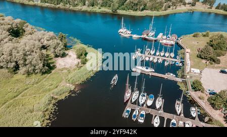 Vue aérienne d'un port de plaisance paisible avec divers voiliers amarrés le long de la jetée, entouré d'une végétation luxuriante par une journée ensoleillée Banque D'Images