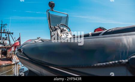 vue rapprochée d'un bateau pneumatique militaire sur le quai avec des grues de navire en arrière-plan sous un ciel bleu clair Banque D'Images