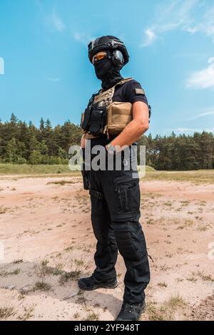 Agents des forces spéciales en équipement tactique pratiquant l'entraînement aux armes à feu dans un champ de tir extérieur sous un ciel nuageux Banque D'Images