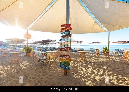 Panneaux en bois colorés en forme de flèche avec des destinations sur le poteau à la plage avec vue panoramique sur le paysage marin Banque D'Images